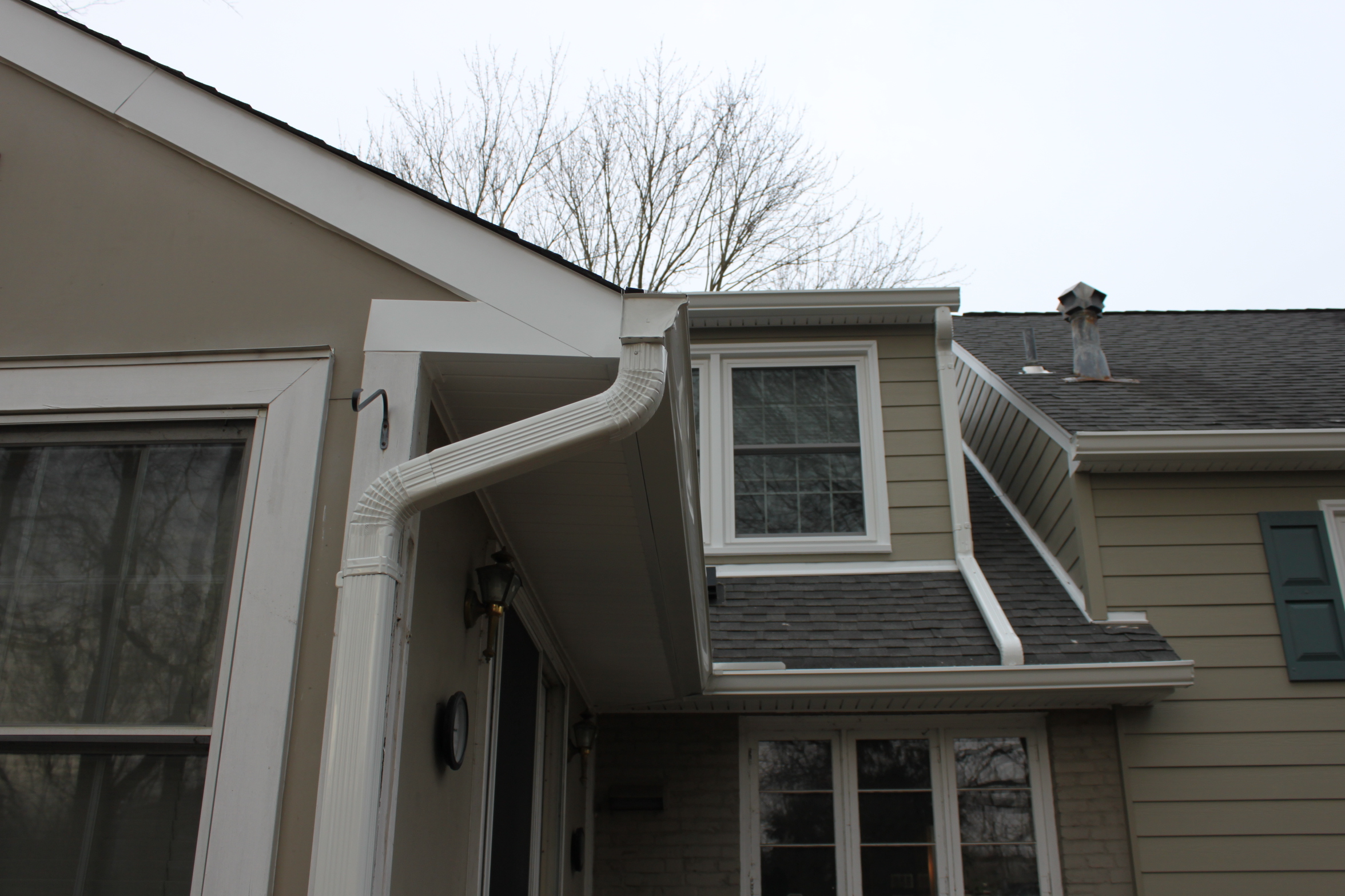 Seamless gutter and fluted downspout installed at a front entry by Sunshine Contracting