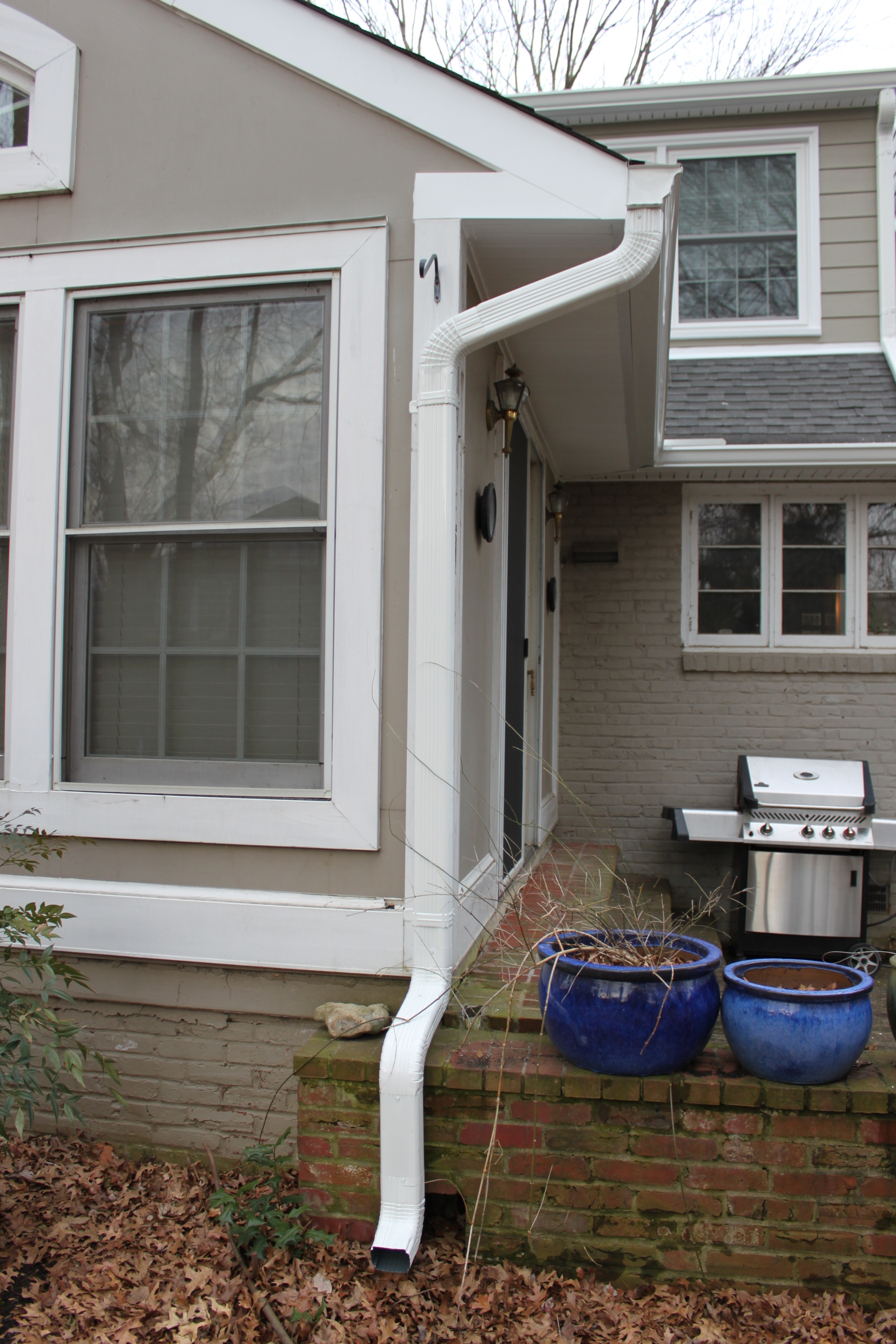 White seamless gutter and downspout installed at a home entry by Sunshine Contracting