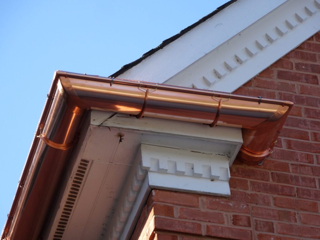 Copper half-round gutter along a brick cornice