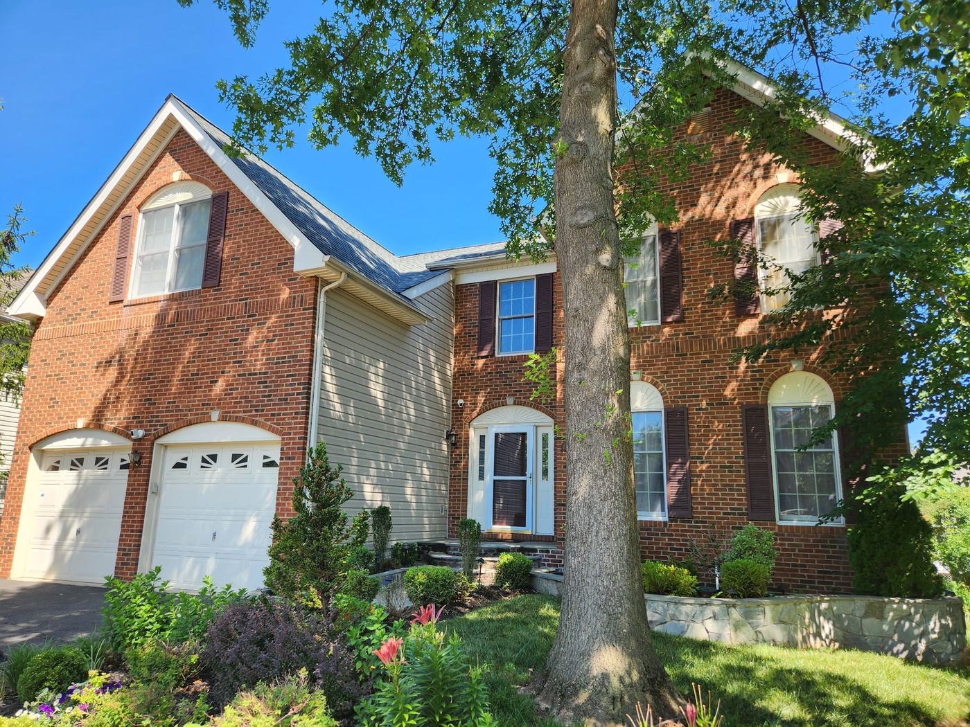 Brick front of a Herndon, VA home after its roof replacement, with vinyl siding on the side wall